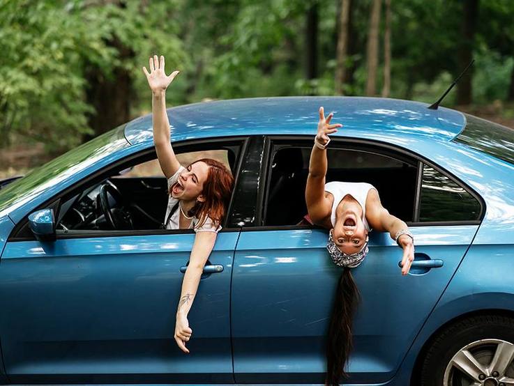 Zwei Frauen strecken ihre Arme aus den offenen Seitenfenstern ihres Autos